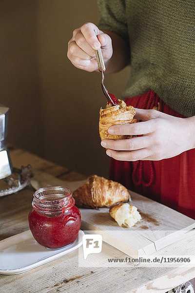 Close-up of woman tasting homemade croissants with jam