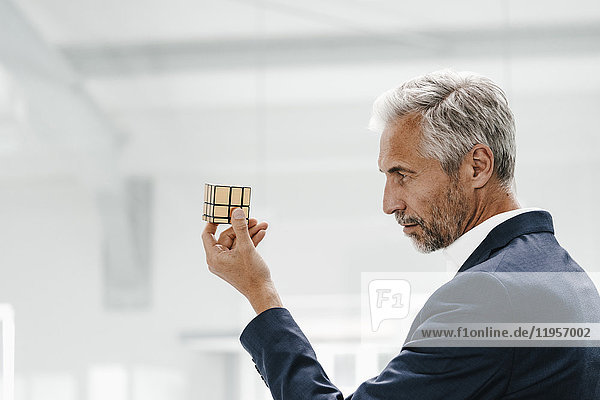 Mature businessman in office examining Rubik's Cube