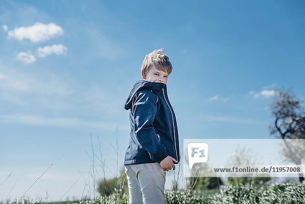 Lächelnder Junge steht vor blauem Himmel