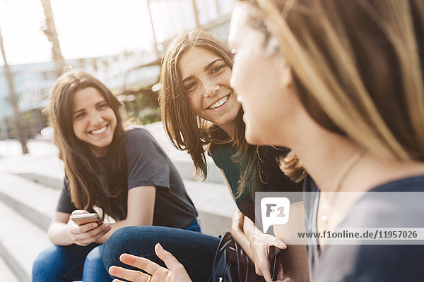 Drei glückliche junge Frauen sitzen im Freien