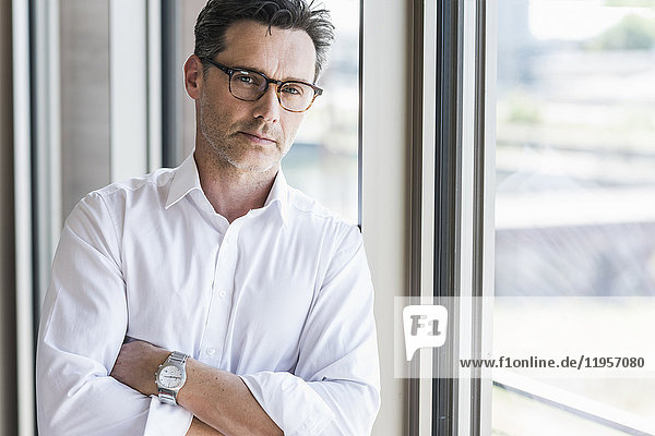 Portrait of sceptical businessman standing in front of window