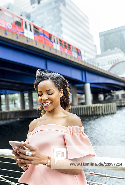 Lächelnde Frau sendet Nachrichten mit ihrem Smartphone in der Stadt