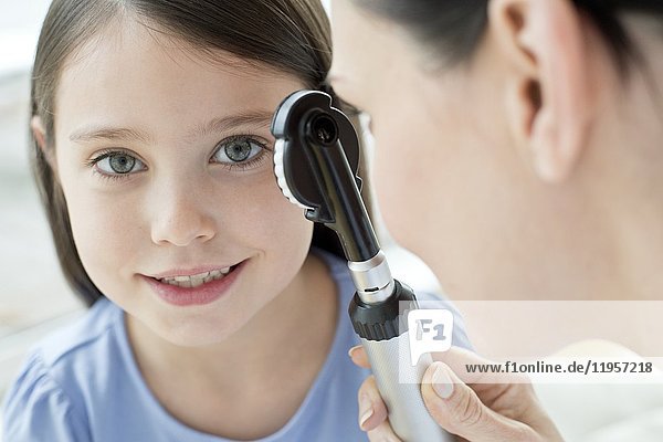 Female doctor examining girl's eye.