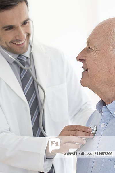 MODELL FREIGEGEBEN. Männlicher Arzt  der einen älteren Patienten untersucht  Porträt.