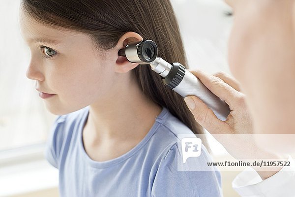 Female doctor examining girl's ear.