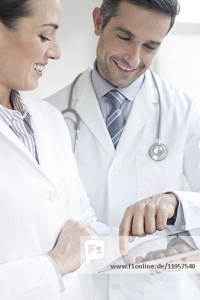 MODELL FREIGEGEBEN. Männliche und weibliche Ärzte mit digitalem Tablet.
