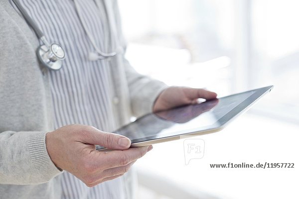 MODELL FREIGEGEBEN. Ärztin mit digitalem Tablet.