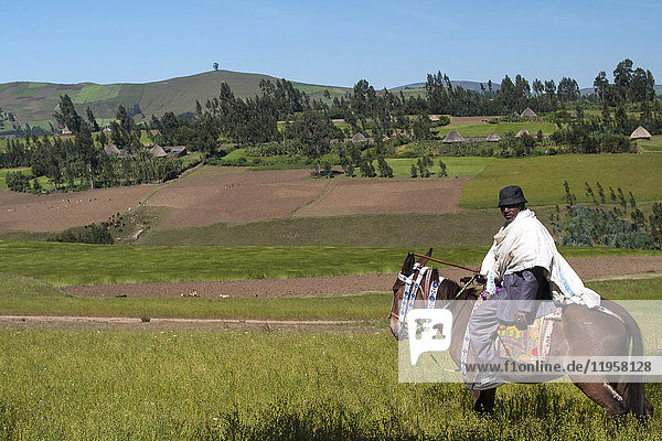 Ein Mann auf dem Pferderücken mit Blick auf die sanften Hügel des ländlichen Äthiopiens  Afrika