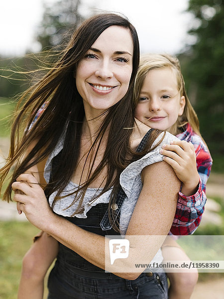 Outdoor portrait of mother playing carrying son (6-7)