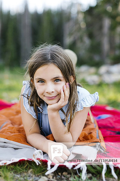 Porträt eines Mädchens (8-9) auf einer Decke liegend im Wald