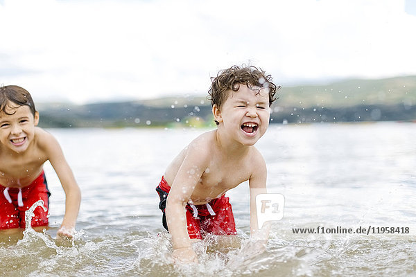 Brothers (4-5  6-7) splashing water in lake