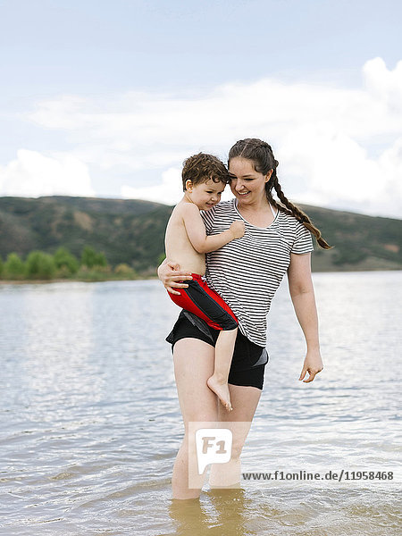 USA  Utah  Park City  Mother carrying son (4-5) while wading in lake