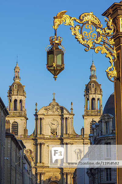Frankreich  Grand Est  Nancy  Verschnörkelte Straßenlaterne mit Kathedrale von Nancy im Hintergrund