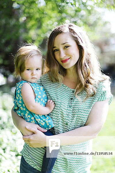 Porträt einer Mutter und eines kleinen Mädchens (12-17 Monate) im Hinterhof