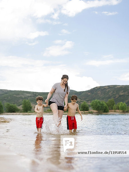 Mother with sons (4-5  6-7) wading in lake