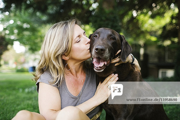 Porträt einer Frau  die einen Labrador Retriever küsst