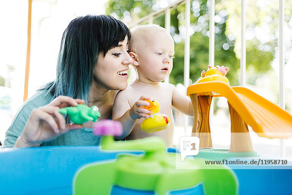 Mutter mit einem kleinen Jungen (12-17 Monate)  der mit aufblasbarem Spielzeug spielt