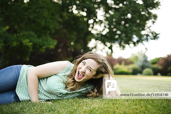 Porträt einer lachenden  im Gras liegenden Frau