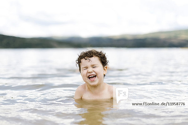 Lächelnder Junge ( 4-5) beim Schwimmen im See