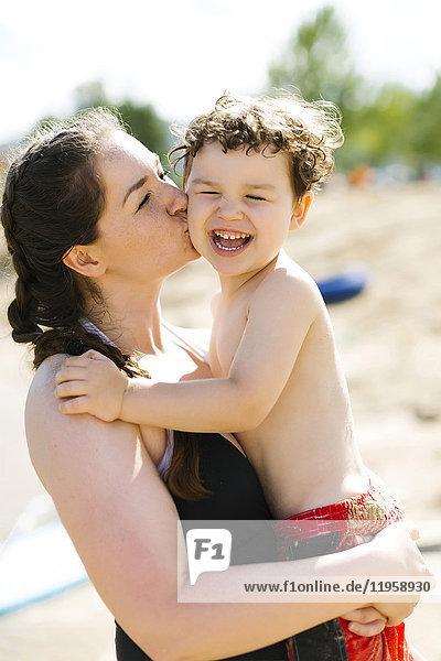 Mother kissing son (4-5) on beach