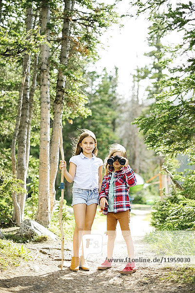Mädchen (8-9) und Junge (6-7) stehen im Wald