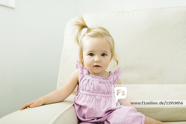Porträt eines kleinen Mädchens (12-17 Monate) auf dem Sofa sitzend