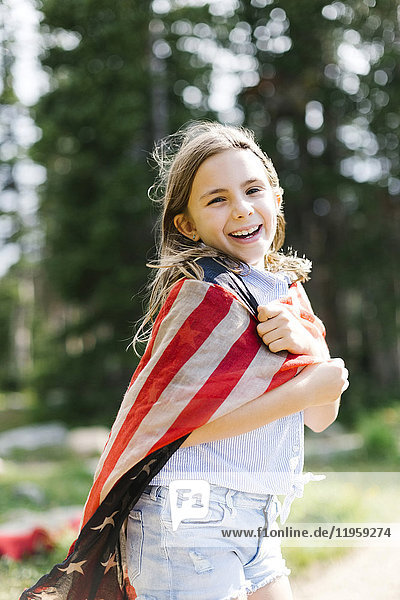 Porträt eines Mädchens (8-9)  eingewickelt in unsere Flagge im Wald
