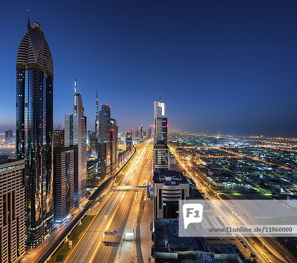 Stadtbild von Dubai  Vereinigte Arabische Emirate in der Abenddämmerung  mit Wolkenkratzern  die die beleuchtete Straße säumen.
