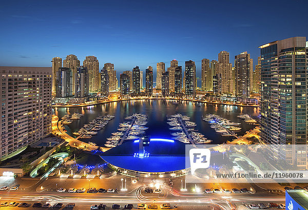 Stadtbild von Dubai  Vereinigte Arabische Emirate in der Abenddämmerung  mit beleuchteten Wolkenkratzern und dem Yachthafen im Vordergrund.