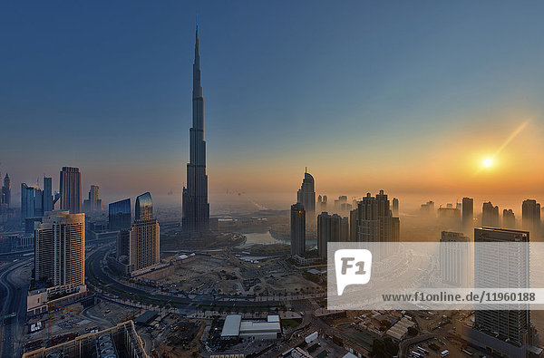 Stadtbild von Dubai  Vereinigte Arabische Emirate in der Abenddämmerung  mit dem Wolkenkratzer Burj Khalifa und anderen Gebäuden im Vordergrund.