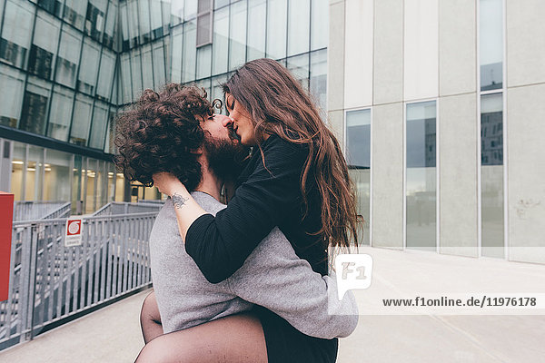 Junges Paar im Freien  küsst sich  die Beine der Frau um den Mann gewickelt