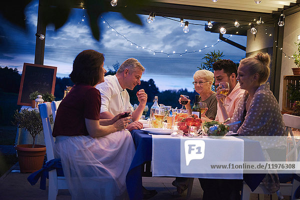 Group of people outdoors  sitting at table  enjoying meal