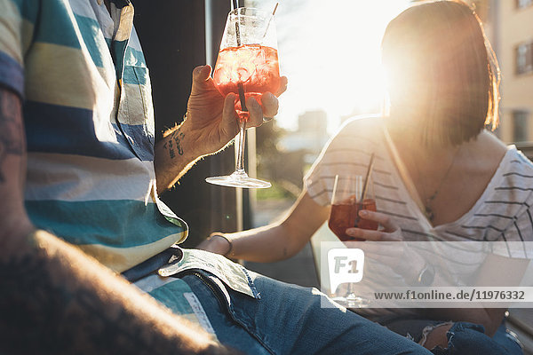 Schnappschuss eines Paares  das vor einem sonnenbeschienenen Straßencafé sitzt und Cocktails trinkt