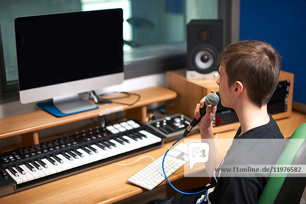 Junger männlicher College-Student spricht im Aufnahmestudio ins Mikrofon
