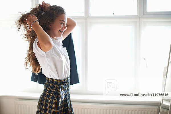 Teenager-Schulmädchen stylt langes Haar im Schlafzimmer
