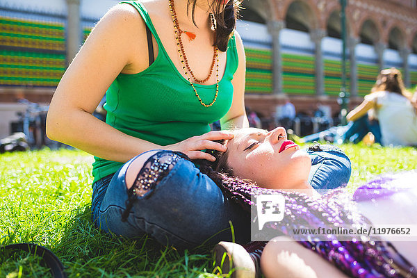 Frau gibt Freundin eine Kopfmassage auf Gras  Mailand  Italien