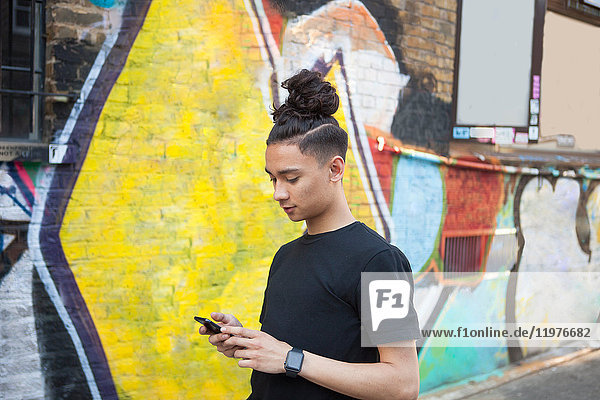 Junger Mann geht im Freien spazieren  benutzt Smartphone