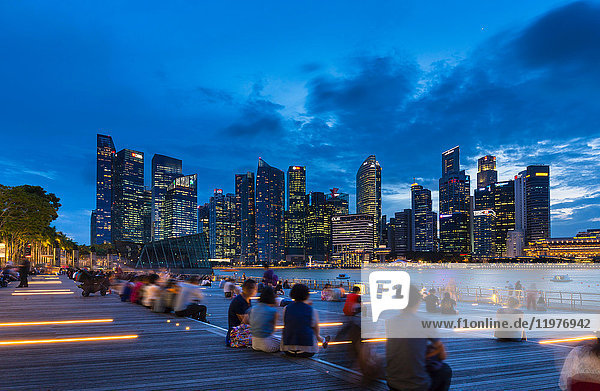 Touristen  die in der Abenddämmerung die Skyline der Stadt vom Wasser aus betrachten  Singapur  Südostasien
