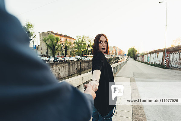 Über-Schulter-Ansicht einer jungen Frau  die am Stadtkanal die Hand ihres Freundes hält