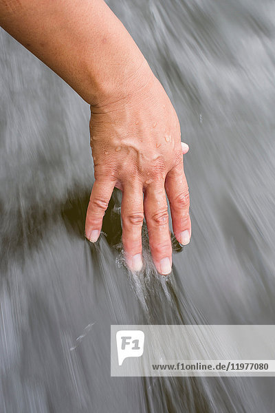 Frau, die die Hand im Wasser zieht