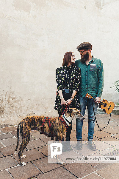 Cooles Paar mit Hund und Ukulele auf dem Bürgersteig