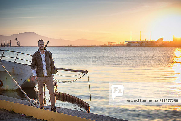 Mann steht bei Sonnenuntergang am Boot und schaut in die Kamera  Cagliari  Sardinien  Italien  Europa