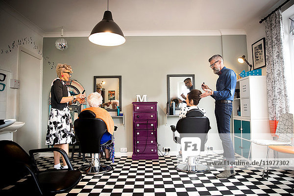 Couple in vintage clothes working on customers in quirky hair salon