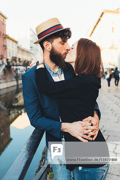 Hipster couple kissing by city canal