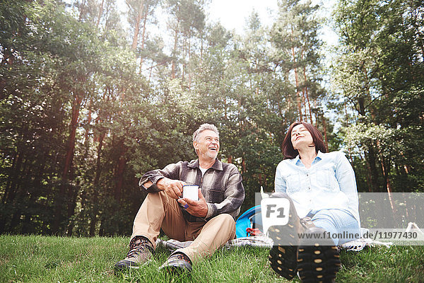 Mature couple relaxing on grass beside tent