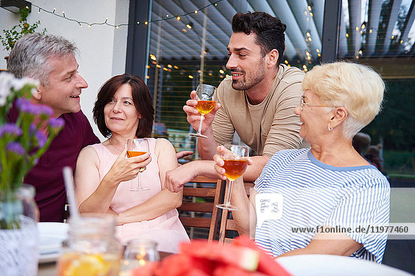 Erwachsene in der Familie im Gespräch und bei Wein zum Mittagessen auf der Terrasse