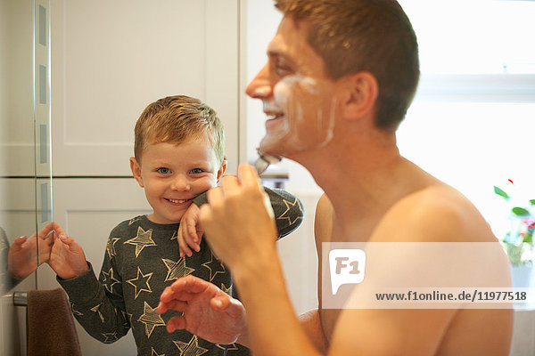 Porträt eines Jungen im Badezimmer mit rasierendem Vater