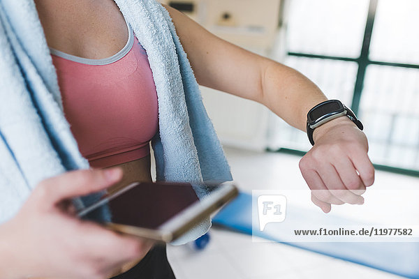 Schnappschuss einer jungen Frau beim Training,  die auf Smartwatch schaut