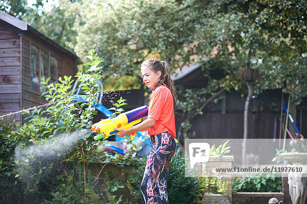 Teenager-Mädchen spritzt Wasserpistole im Garten