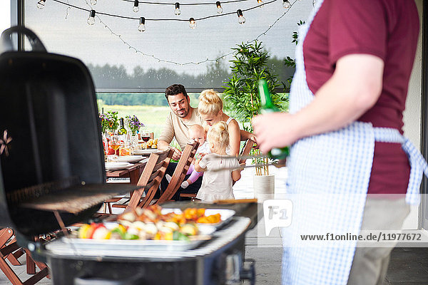 Man barbecuing at family lunch on patio